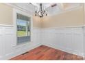 This dining room features wainscoting, hardwood floors, a stylish chandelier, and a bright window at 135 Waycross Dr, Rockwell, NC 28110