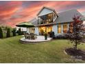 Spacious backyard featuring a stone patio with outdoor seating, lush lawn, and manicured landscaping at 14128 Morningate St, Huntersville, NC 28078