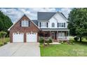 Charming two-story brick home featuring a covered front porch, beautiful landscaping, and attached two-car garage at 2779 Touchstone Cir, Newton, NC 28658