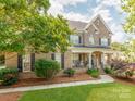 Charming brick home boasts a covered front porch, lush lawn, and mature trees, creating a warm, inviting curb appeal at 537 Montgrove Nw Pl, Concord, NC 28027