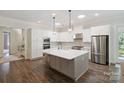 Bright kitchen features white cabinets, stainless steel appliances, a large island, and wood floors at 5590 Elk Knob Ct, Denver, NC 28037