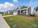 A charming blue house sitting on a well manicured lawn and landscaped with flowering plants at 6015 Waldorf Ave, Monroe, NC 28110