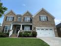 Charming two-story brick home with a well-manicured lawn, a two car garage, and a welcoming front porch at 707 Five Leaf Ln, Waxhaw, NC 28173
