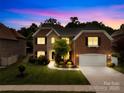 Beautiful two-story brick home with a manicured lawn and an attached two-car garage at dusk at 8460 Fairgreen Ave, Waxhaw, NC 28173