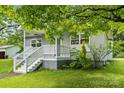 Charming home featuring a quaint porch, light gray siding, complemented by a well-maintained lawn and mature trees at 935 Church St, Kings Mountain, NC 28086