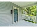 Inviting porch with lattice railing leading to a front door with sidelight and view of trees at 935 Church St, Kings Mountain, NC 28086