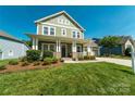 Charming two-story home featuring a welcoming front porch, well-maintained lawn, and lush landscaping at 11324 Fullerton Place Nw Dr, Huntersville, NC 28078
