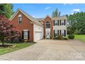 Charming two-story brick home with manicured landscaping, a driveway, and an attached two-car garage at 13528 Philip Michael Rd, Huntersville, NC 28078