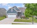 Charming exterior with blue siding, stone accents, manicured lawn, and two car garage at 1663 Tranquility Blvd, Lancaster, SC 29720