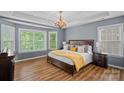 Comfortable main bedroom with a tray ceiling, chandelier, hardwood floors, and large windows at 1849 Still Water Ln, Indian Land, SC 29707