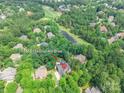 Aerial view of home with a pool, surrounded by lush trees, near a golf course at 1868 Chestnut Hill Dr, Tega Cay, SC 29708