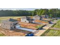 New construction homes line a street showcasing the neighborhood's layout and surrounding wooded area at 21055 Running Creek Dr # 10, Locust, NC 28097