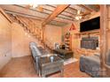 Cozy living room features brick fireplace, wood paneled walls, exposed beam ceiling, and staircase to upper level at 417 Phifer Rd, Kings Mountain, NC 28086