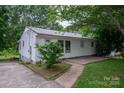 Side view of a cozy home with white siding, metal roof, concrete patio, and walkway to the driveway at 535 Norman Fair Ave, Lincolnton, NC 28092