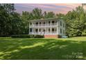 Beautiful two-story home at sunset, surrounded by mature trees and a well-manicured green lawn at 704 Little Creek Dr, Kings Mountain, NC 28086