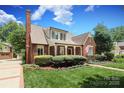 A beautiful brick home featuring a manicured lawn and lush landscaping under a partly cloudy sky at 1021 Isleworth Ave, Charlotte, NC 28203