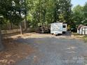 Camper and outdoor seating area on a gravel lot, surrounded by trees and fence at 103 Powder Horn Trl, Mount Gilead, NC 27306