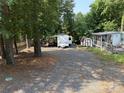 Camper on a gravel lot, surrounded by trees, a shed, and a screened-in porch at 103 Powder Horn Trl, Mount Gilead, NC 27306