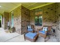Charming covered porch with brick, inviting seating area with wicker chairs and blue cushions at 110 St Sophia Ct, Mooresville, NC 28117