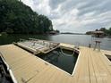 Lakeside dock with boat lift on a calm, scenic lake under a cloudy sky, perfect for outdoor enthusiasts at 150 Pinnacle Shores Dr, Mooresville, NC 28117