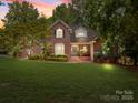 Charming brick two-story home with lush landscaping and a sprawling front lawn at sunset at 150 Pinnacle Shores Dr, Mooresville, NC 28117