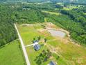 Expansive aerial view of a property featuring a home, a pond, lush green fields, and surrounding woodlands at 2737 Bobcat Rd, Heath Springs, SC 29058