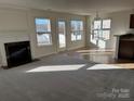 Inviting living room featuring a cozy fireplace, large windows, and seamless transition to the dining area at 3244 Oulten Sw St, Concord, NC 28027