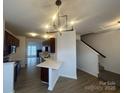 Open concept kitchen with white countertops, dark cabinets, and modern light fixture near stairs at 4208 Coulter Xing, Charlotte, NC 28213
