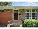 Front exterior with stone accents, a brick facade, landscaped bushes, and a tiled front step at 4232 Randolph Rd, Charlotte, NC 28211