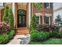 Elegant brick home featuring a secure front entrance with a dark arched double door and manicured landscaping at 8500 Headford Rd, Charlotte, NC 28277