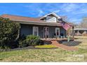 Charming home with a cozy front porch, manicured landscaping, and patriotic American flag display at 101 Sunset Dr, Stanley, NC 28164