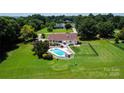 Aerial view of a home featuring a sparkling blue swimming pool, spacious backyard, and lush green surroundings at 205 Harwell Rd, Mooresville, NC 28117