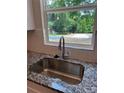 Close-up of a stainless steel kitchen sink with granite countertops, complemented by a window view of the backyard at 242 North Ave, Troutman, NC 28166