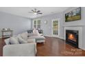 Bright living room with hardwood floors, a fireplace, ceiling fan, and a comfortable gray sectional sofa at 3230 Yarmouth Ln, Gastonia, NC 28056