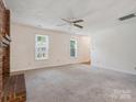 Spacious living room with a cozy brick fireplace, neutral carpet, bright windows, and a ceiling fan at 3313 Fortis Ln, Matthews, NC 28105