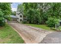 View of exterior showing a long driveway leading to a charming home surrounded by lush greenery and mature trees at 3884 Snider Cir, Hickory, NC 28602