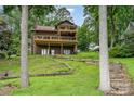 Two-story lake house with multiple wooden decks, accessible by terraced stairs through a grassy yard at 6719 Love Point Rd, Denver, NC 28037