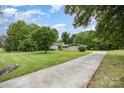 Long concrete driveway leads to a single-story home with manicured lawn, mature trees, and inviting curb appeal at 985 Needmore Rd, Woodleaf, NC 27054