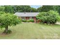 Aerial view of a charming brick ranch home featuring a well-manicured lawn and mature trees at 115 Turner St, Lincolnton, NC 28092