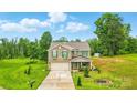 Beautiful two-story home featuring a brick facade, green shutters, and a spacious front yard with lush trees at 124 Vintage Woods Ct, Shelby, NC 28150
