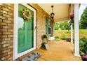 Close-up of a charming front porch with a decorated green door, brick wall, and a hanging lantern at 124 Vintage Woods Ct, Shelby, NC 28150