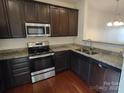 Modern kitchen showcasing granite countertops, stainless steel appliances, and dark wood cabinets at 15239 Wrights Crossing Dr, Charlotte, NC 28278