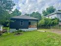 Charming home featuring a decorative wood porch, black siding, and a well-maintained front yard at 16 Cherry St, Albemarle, NC 28001