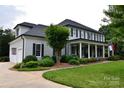 Side view of a gray two-story home with a white garage, front porch, and manicured lawn at 19625 Callaway Hills Ln, Davidson, NC 28036