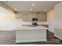 Open kitchen featuring an island with a sink, gray cabinets, stainless steel appliances, and wood flooring at 213 J.P. Dr, Albemarle, NC 28001