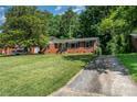 Charming brick home with mature trees, a well-maintained lawn, and a private driveway at 3939 Sheffield Dr, Charlotte, NC 28205