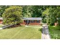 Beautiful brick home with lush green lawn and mature trees offering shade at 3939 Sheffield Dr, Charlotte, NC 28205