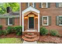 Inviting front porch with brick steps and a covered entrance, complemented by green shutters and lush landscaping at 626 Trail Ridge Rd, Matthews, NC 28105