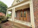 Inviting front porch with brick flooring, white columns, wood door, and outdoor seating at 8620 Rolling Fields Rd, Charlotte, NC 28227
