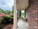 Relaxing covered front porch with brick and painted columns, wicker seating and manicured landscaping at 8620 Rolling Fields Rd, Charlotte, NC 28227